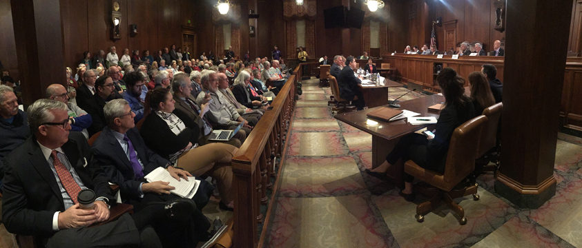 A packed committee room listens to testimony